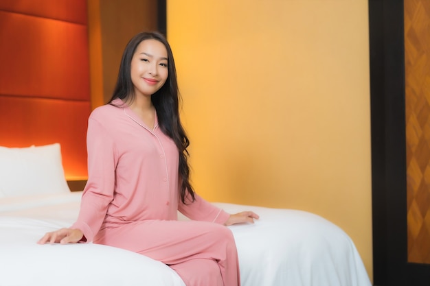 De portret mooie jonge aziatische vrouw ontspant glimlach gelukkig op bed in slaapkamerbinnenland