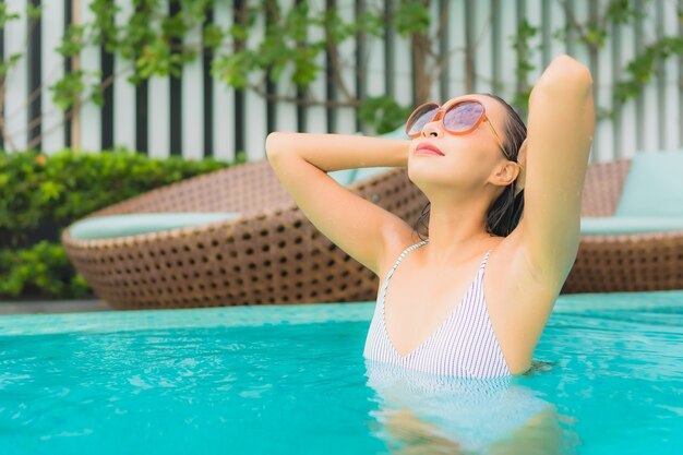 De portret mooie jonge aziatische vrouw ontspant vrije tijd rond openluchtzwembad in hoteltoevlucht voor reisvakantie