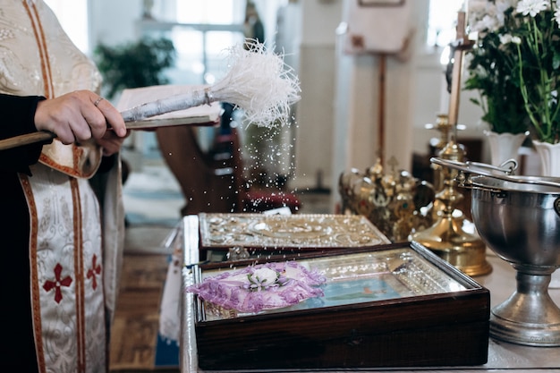 De priester bestrooit wijwater op trouwringen in kerk
