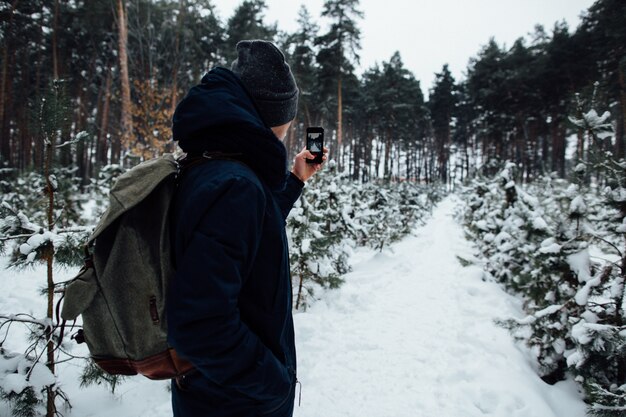 De reiziger neemt selfie van sneeuwlandschap in de winterbos op mobiele telefoon