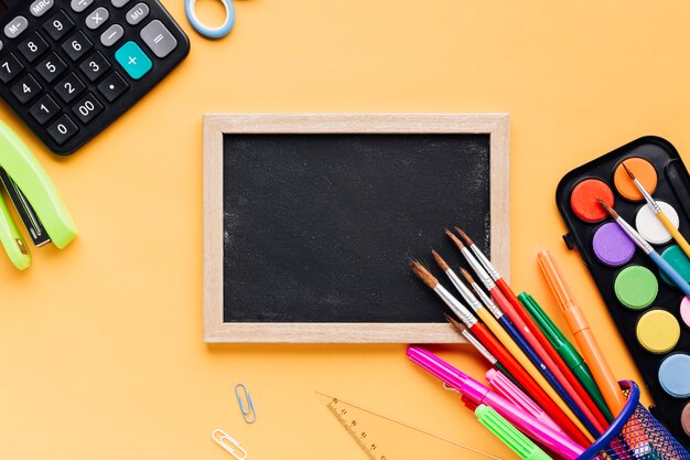 De schoollevering verspreidde zich rond leeg ontworpen bord op geel bureau