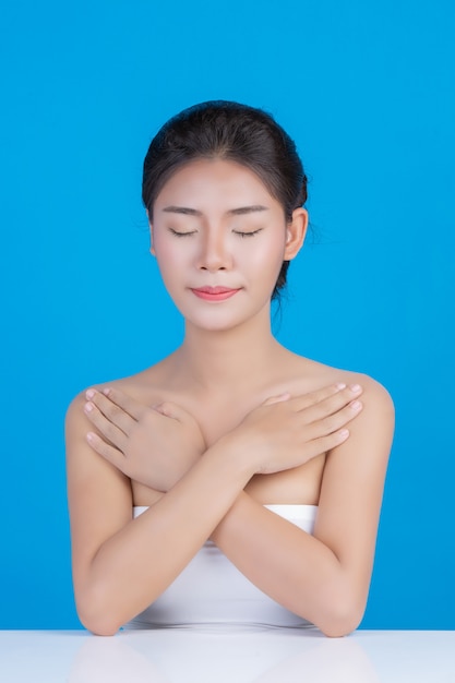 De schoonheid van vrouwen met perfecte huidgezondheidsbeelden Haar gezicht aanraken en glimlachen als een spa om haar huid te verwennen Blauw