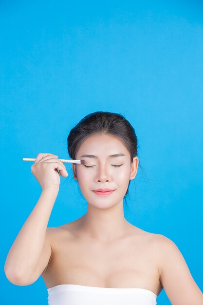 De schoonheid van vrouwen met perfecte huidgezondheidsbeelden Haar gezicht aanraken en glimlachen als een spa om haar huid te verwennen Blauw