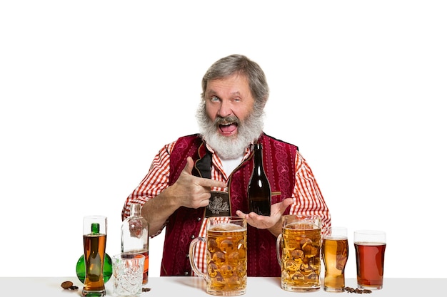 Gratis foto de senior deskundige mannelijke barman met bier in de studio op wit wordt geïsoleerd