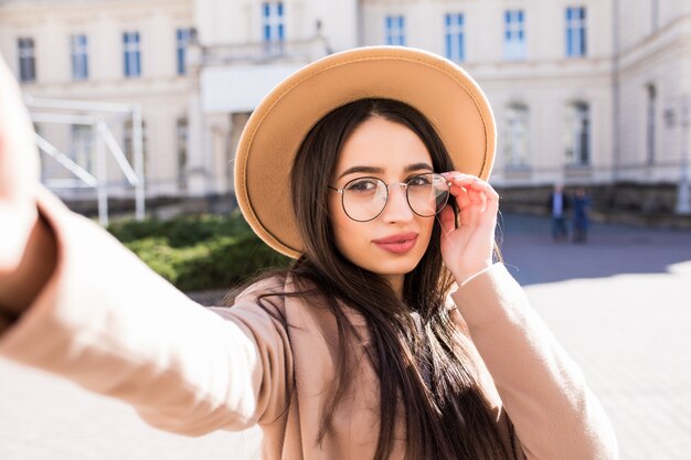 De sexy modelvrouw maakt in openlucht selfie op haar nieuwe smartphone in de stad in zonnige dag