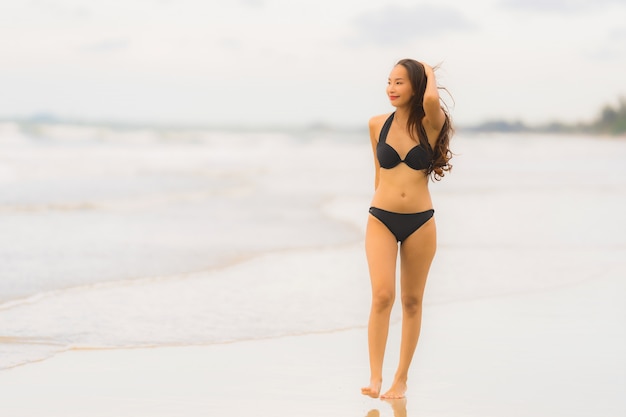 De slijtagebikini van de portret mooie jonge Aziatische vrouw op de strand overzeese oceaan