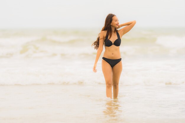 De slijtagebikini van de portret mooie jonge Aziatische vrouw op de strand overzeese oceaan