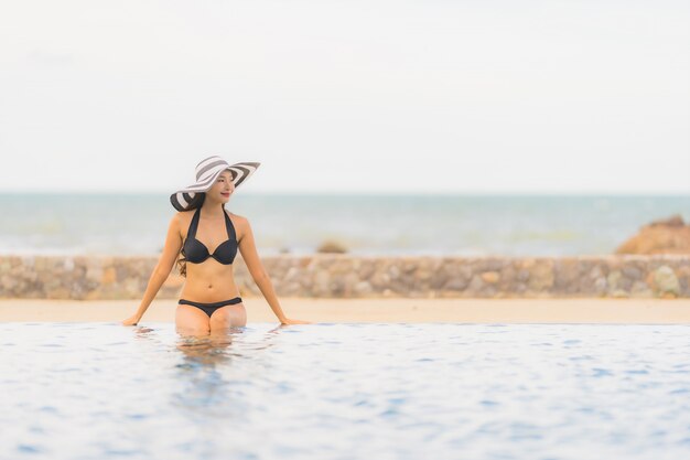 De slijtagebikini van de portret mooie jonge Aziatische vrouw rond zwembad in hoteltoevlucht bijna overzees oceaanstrand