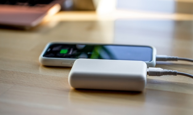 Gratis foto de smartphone wordt via een snoer opgeladen vanaf een kleine witte powerbank.