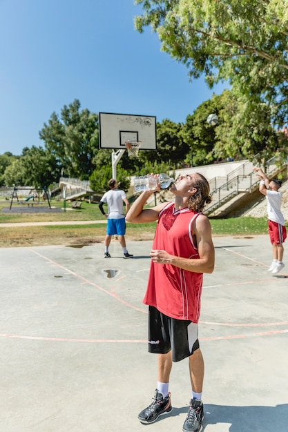 De speler drinkwater van de basketbal van fles bij openluchthof