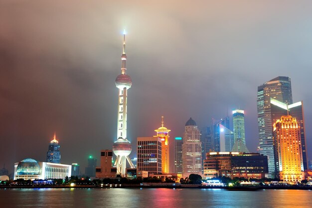 De stadshorizon van Shanghai bij nacht over Huangpu-rivier