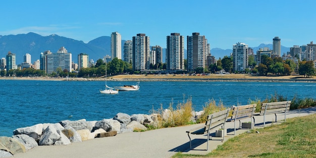 De stadshorizon van Vancouver aan de waterkant met bank in park