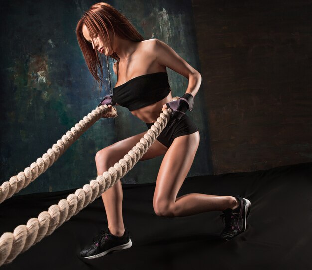 Gratis foto de sterke jonge vrouw die touw trekt bij een gymnastiek