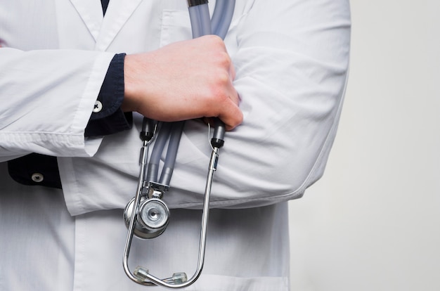De stethoscoop van een de handholding van een mannelijke arts in hand tegen witte achtergrond