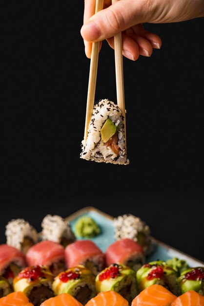 De sushi van de persoonsholding met eetstokjes