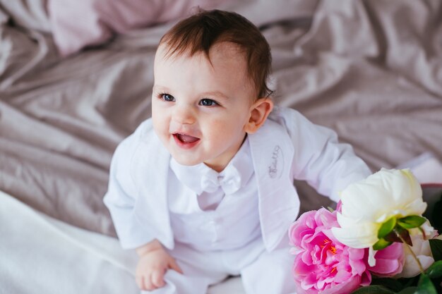 De tederheid jongen met bloemen zittend op het bed