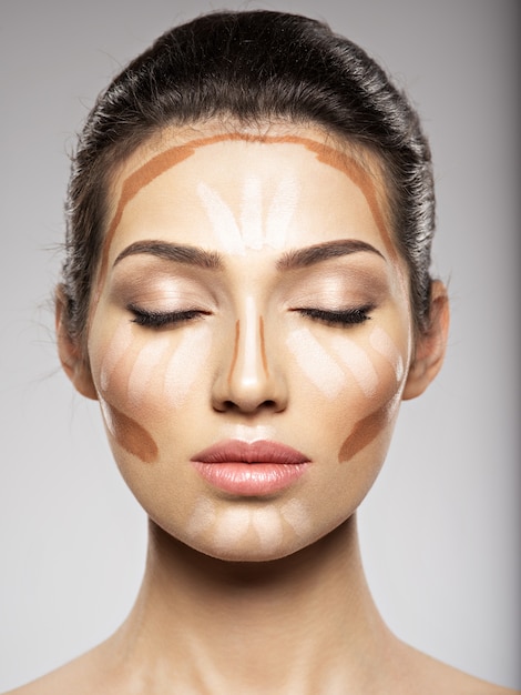 De tonale foundation van de cosmetische make-up is op het gezicht van de vrouw. Schoonheidsbehandeling concept. Meisje maakt make-up.