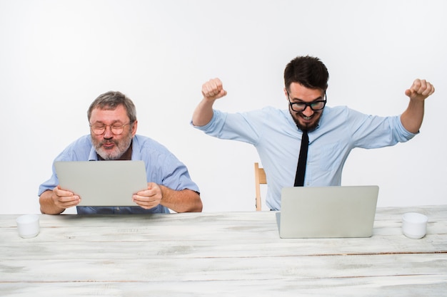 De twee collega's die op kantoor aan witte muur samenwerken