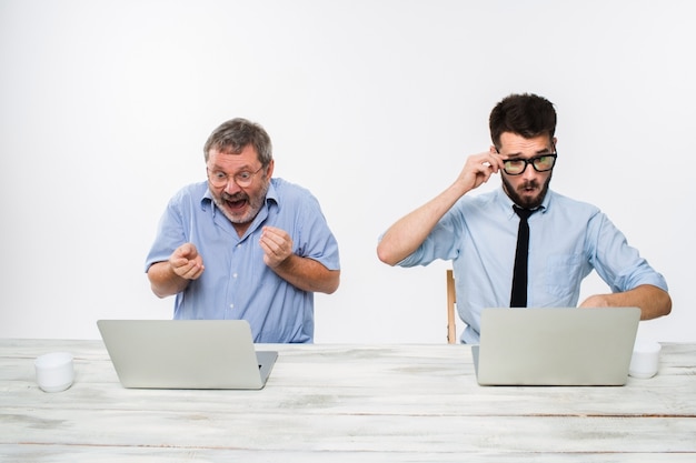 De twee collega's die op kantoor aan witte muur samenwerken