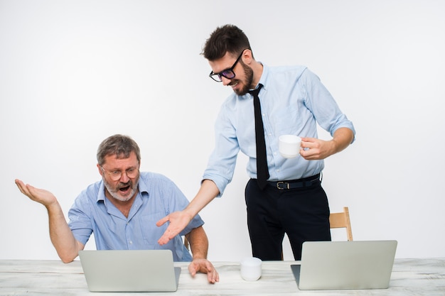 De twee collega's die op kantoor aan witte muur samenwerken