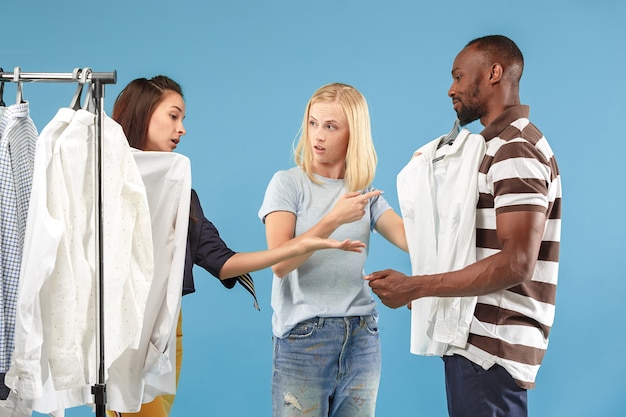 De twee jonge mooie meisjes kijken naar jurken en passen het terwijl ze in de winkel kiezen