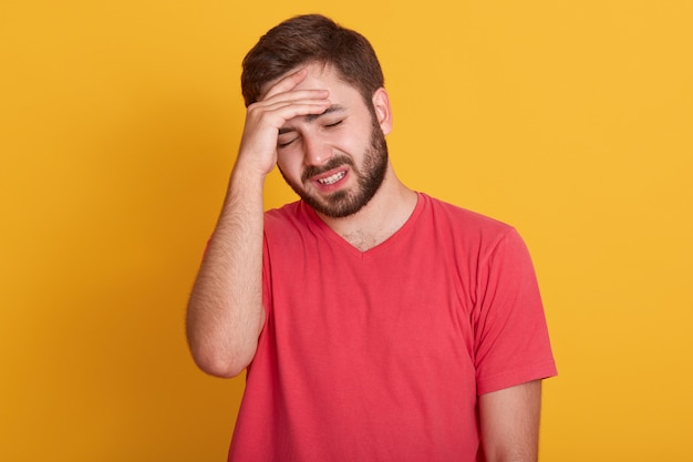 De vermoeide jonge mens houdt hand op voorhoofd