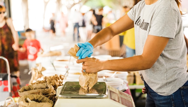 Gratis foto de verpakkingsvoedsel van de vrouwenverkoper voor haar klant in markt