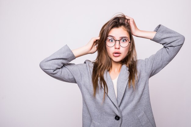 De verwarde vrouw zet haar handen op het hoofd, dat op witte achtergrond wordt geïsoleerd