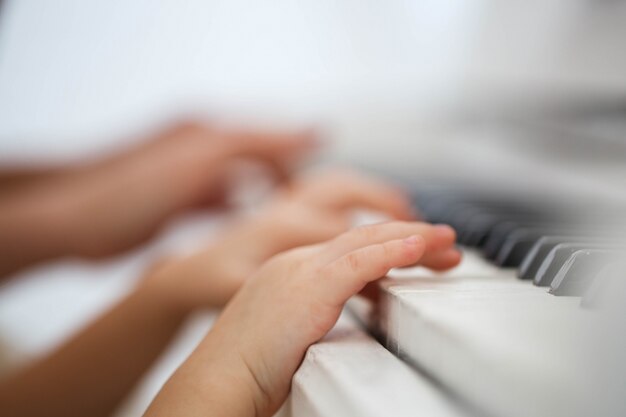 De vingers van het kind zetten pianosleutels aan