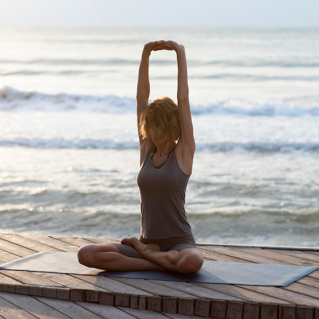 Gratis foto de volledig geschoten vrouw die sukhasana doet stelt openlucht