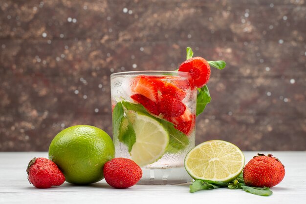 De vooraanzichtkalk en de aardbeien vers en zacht met glas water op wit, fruitbes drinken tropische citrusvruchten