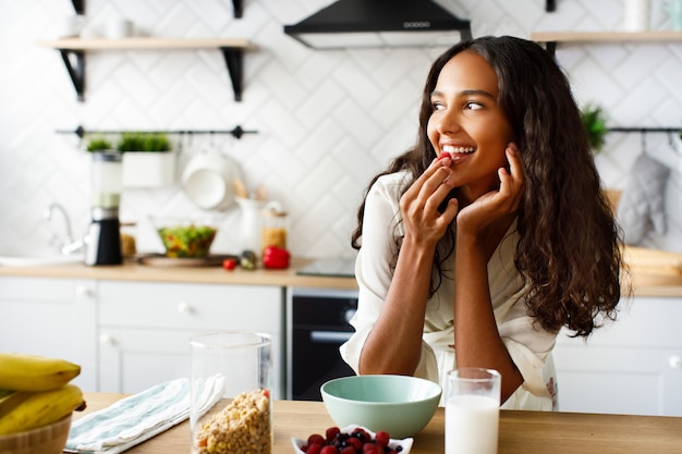 De vrij afrikaanse vrouw eet een framboos vóór een ontbijt