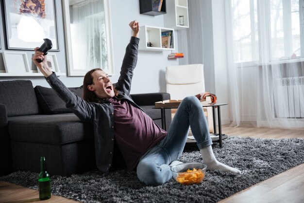 De vrolijke mensenzitting thuis speelt binnen spelen met bedieningshendel