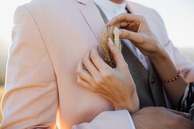 De vrouw bevestigt een modieus bruids knoopsgat aan een man