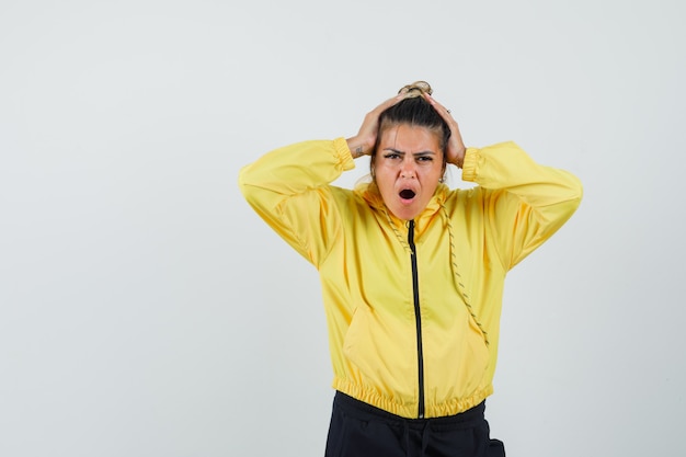 De vrouw die het hoofd in handen in sportkostuum vastklemt en spijtig, vooraanzicht kijkt.