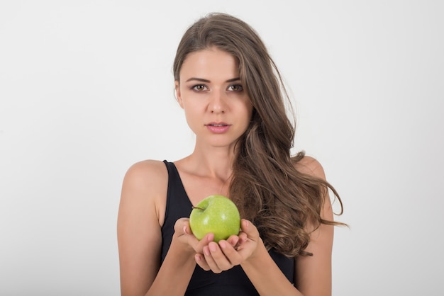 De vrouw die van de schoonheid groene appel houdt terwijl geïsoleerd op wit