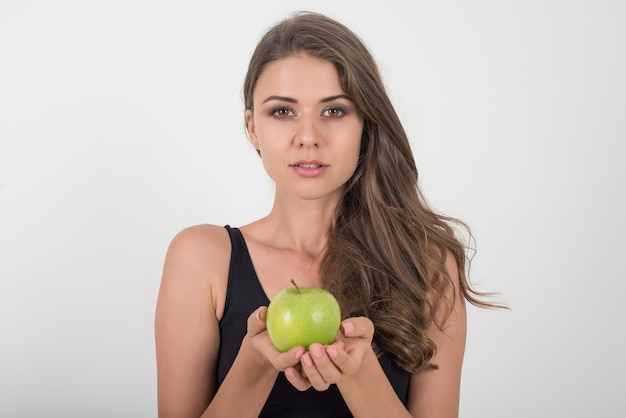 De vrouw die van de schoonheid groene appel houdt terwijl geïsoleerd op wit