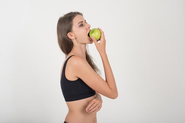 De vrouw die van de schoonheid groene appel houdt terwijl geïsoleerd op wit