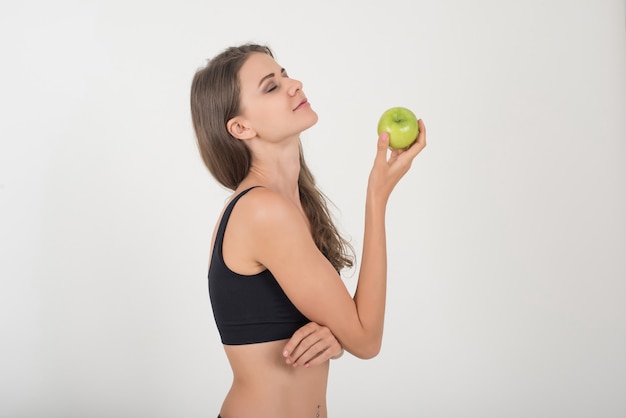 De vrouw die van de schoonheid groene appel houdt terwijl geïsoleerd op wit