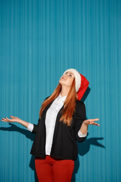 De vrouw die van Kerstmis een kerstmuts draagt en omhoog kijkt