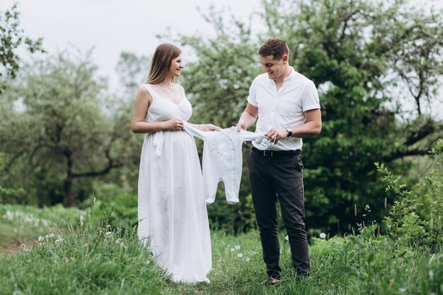 De vrouw en de echtgenoot houden babyachtige kleding en lopen langs het steegje