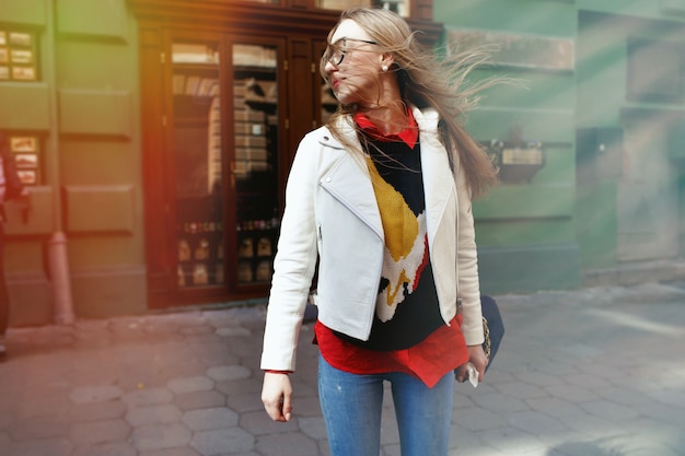 Gratis foto de vrouw gekleed in toevallige stijl loopt op de straat met groene huizen