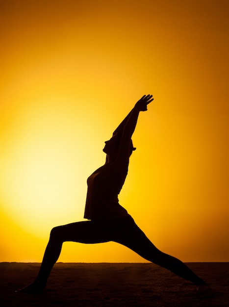 De vrouw het beoefenen van yoga in de zonsondergang licht