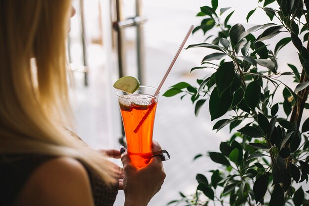 Gratis foto de vrouw houdt aardbeicocktail die met appelplakken wordt versierd