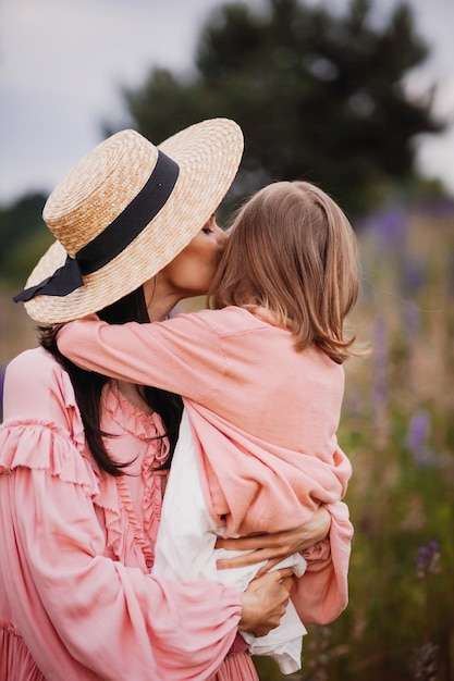 De vrouw in hooihoed houdt meisje op haar wapens die zich op het gebied bevinden