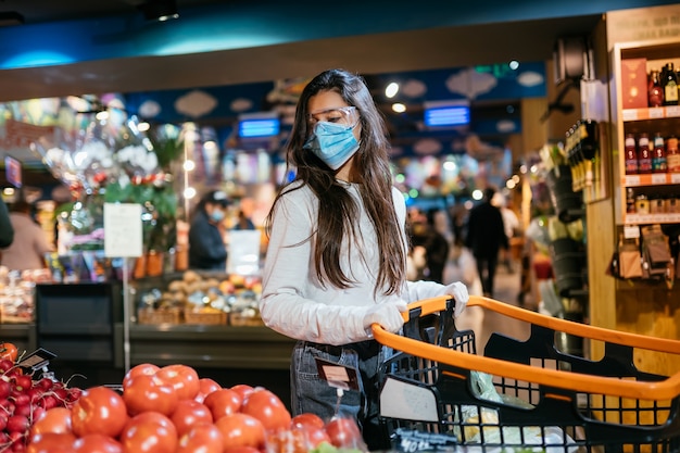 De vrouw met chirurgisch masker gaat tomaten kopen