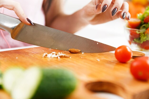 De vrouw snijdt amandelen op de houten raad