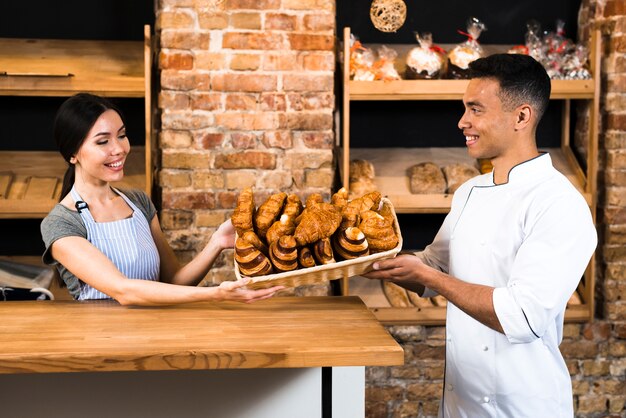 De vrouwelijke en mannelijke mand van de bakkersholding van gebakken croissant in de patisserie