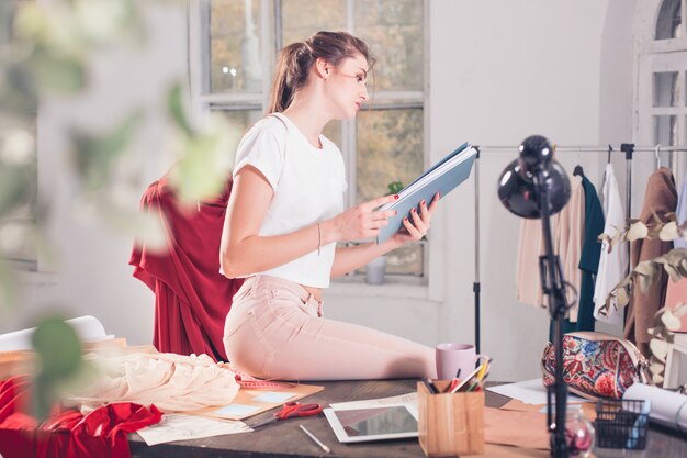 De vrouwelijke modeontwerper die in studiozitting op het bureau werkt