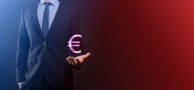 De zakenman houdt geldmuntpictogrammen eur of euro op donkere toonachtergrond... groeiend geldconcept voor bedrijfsinvesteringen en financiën